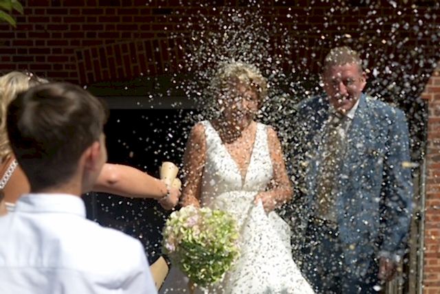 Hurley House - A bride holding a bouquet and a groom in a suit are showered with confetti at a luxury wedding venue in Berkshire. They smile as a young man in a white shirt and a woman with blonde hair join the celebration outside the charming brick building.